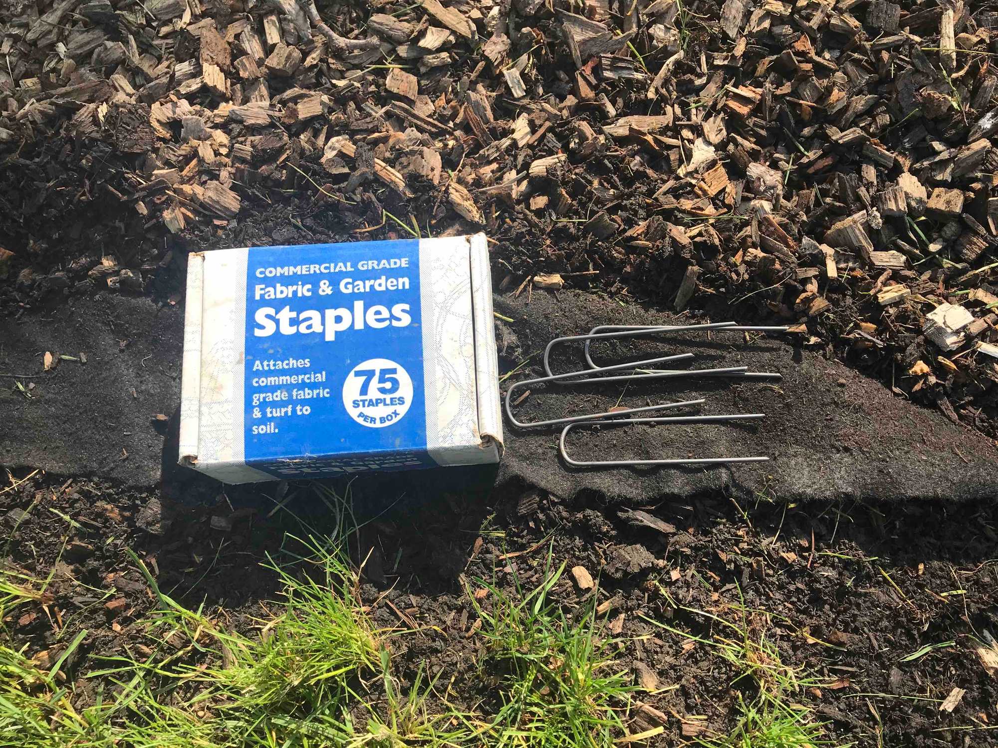 Black weed fabric edge sticking out of mulch